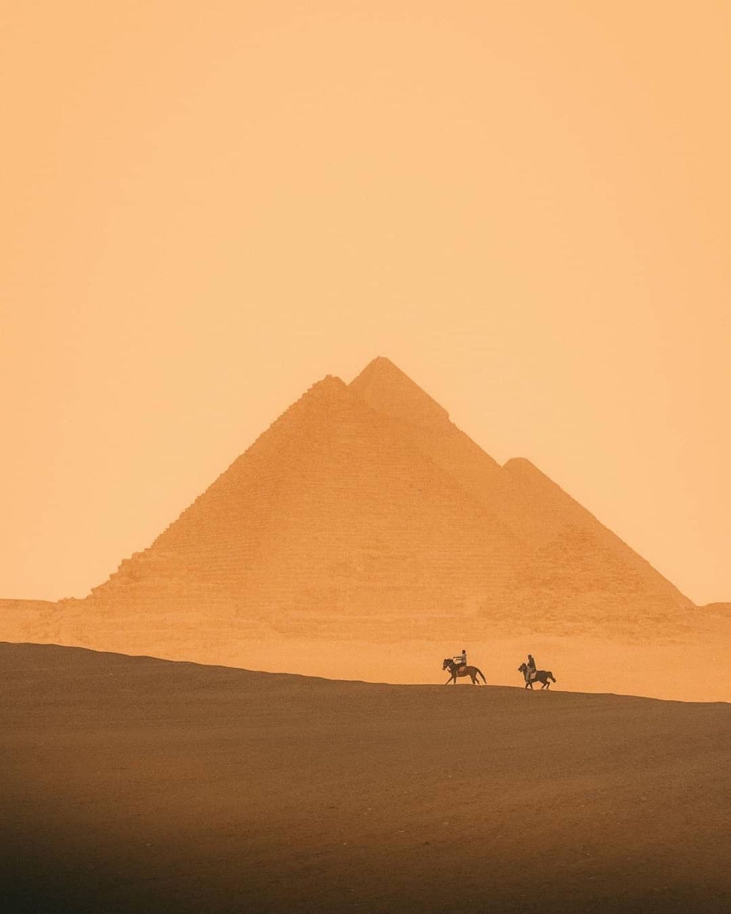 Horseback riders at the pyramids at sunset
